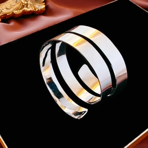 Macro detail of silver multi-layered spiral bangle with polished mirror finish on black stand