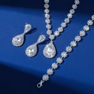 Close-up of sparkling necklace, earrings, and bracelet set on a textured blue pedestal