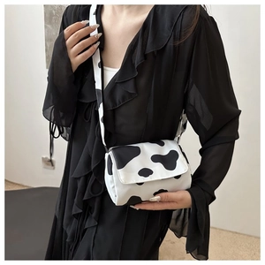 Chic cow print crossbody bag styled on a black dress with adjustable white strap