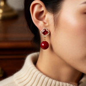 Detailed view of vintage flower earrings with red crystals and pearls on model