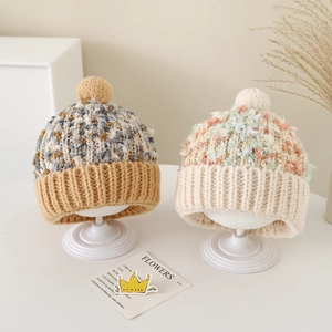 Winter gebreide mutsen voor kinderen met kleurrijke pompons en geribbelde randen op stand