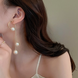 Detailed view of long gold tassel earrings with pearls worn by a fashion model