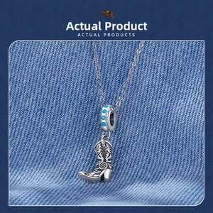 Close-up of vintage silver cowboy boot pendant with blue stone on denim background