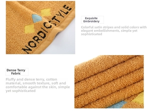 Detail of Nordic style embroidery and dense cotton loops on thick orange bath towel