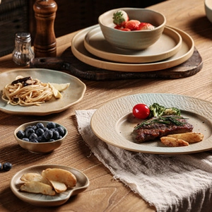 Artistic cream ceramic flower tray with rustic steak and pasta display on wooden table