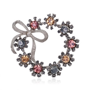 Macro detail of silver wreath brooch with multi-colored crystals and bow decoration