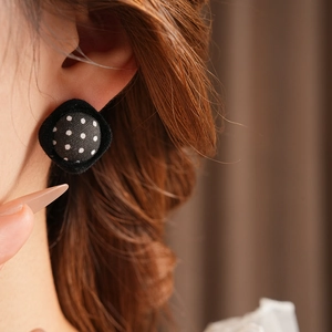 Close-up of retro black and white polka dot fabric square earrings on model