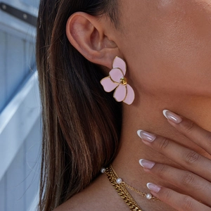 Pink enamel flower earrings with gold trim on model, stylish stainless steel floral jewelry