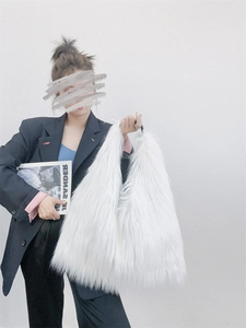 Close-up of white faux fur tote bag with plush texture held by a model on white background