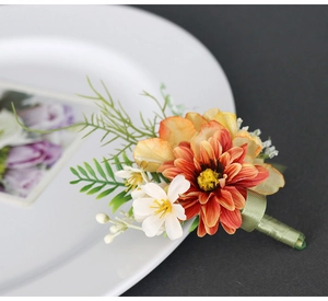Detailed view of artificial corsage with orange dahlia and green ribbon wrapped stem