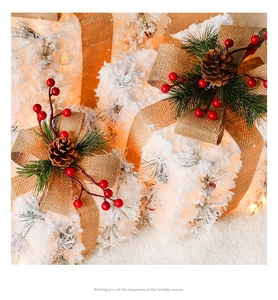 Detail of a lighted Christmas gift box with snow texture, pine cones and burlap bow