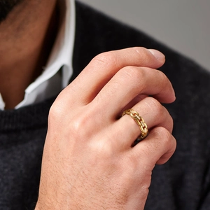 Close-up of a gold chain-link ring set with cubic zirconia worn on a man's finger