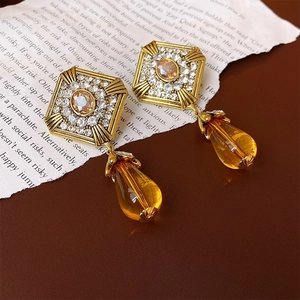 Dettaglio di orecchini vintage dorati con pendenti in cristallo ambra su carta antica