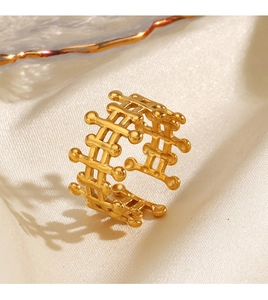 Detail of gold-plated hollow mesh ring with beaded edges on silk background