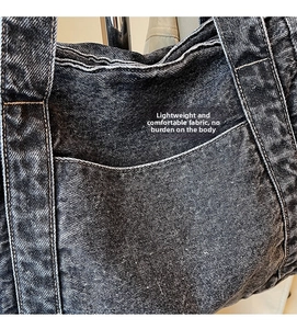 Detail of grey denim tote bag showing washed fabric texture and large front pocket
