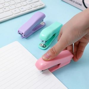 Mini macaron-colored staplers in pink, green, and purple being used on notebook