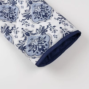 Detailed close-up of blue paisley pattern and trim on the white cotton coat cuff