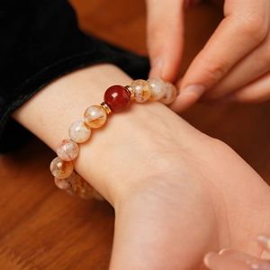 Gros plan détaillé du bracelet en perles marbrées orange-blanc et accents dorés