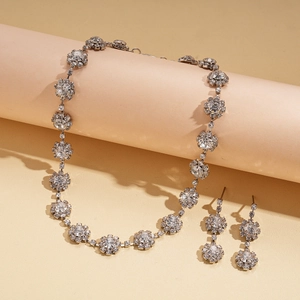 Sparkling silver floral jewelry set with necklace and earrings on beige background