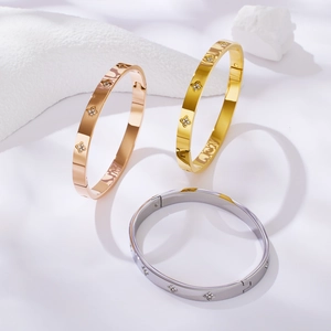 Three elegant stainless steel clover bracelets in rose gold, gold, and silver with crystals