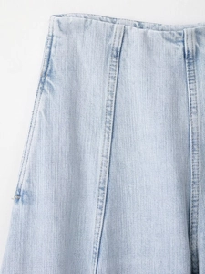 Detailopname van de hoge taille en gewassen lichtblauwe denimstof met fijne stiksels