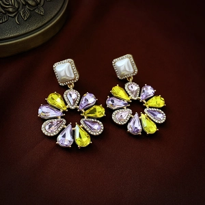 Détail de boucles d'oreilles fleuries avec cristaux jaunes et violets sur cuir