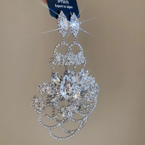 Détail des boucles d'oreilles fleur argentée avec strass scintillants et pompons