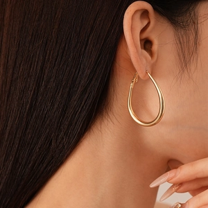 Macro view of gold teardrop hoop earrings showing polished finish and sleek metal texture