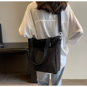 Detail of adjustable strap and side pocket on a minimalist black canvas tote bag
