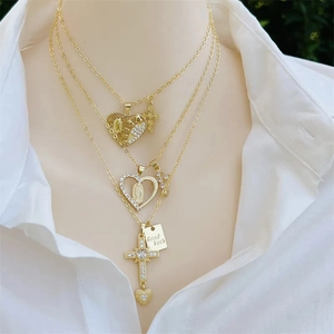 Close-up of 18K gold plated layered necklaces with cross, Virgin Mary, and heart pendants
