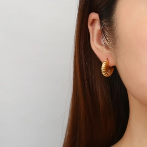Detail shot of vintage gold C-shape stud earrings with grooved shell-like texture on model
