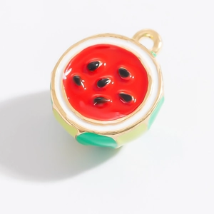 Vue macro du pendentif pastèque en émail avec bordure dorée et détails de fruits