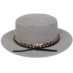 Detail of grey straw hat with golden metal chain and black ribbon bow accent