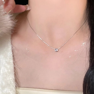 Close-up of silver zircon flower pendant necklace worn on a model's collarbone