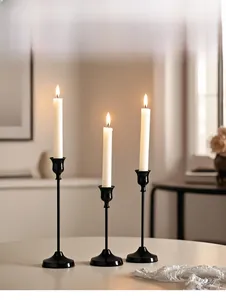 Detailed view of three black metal candle holders in varying heights with lit candles