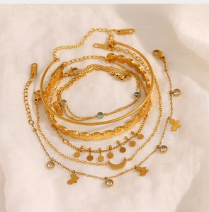 Macro shot of gold layered bracelets with moon pendants and S.STEEL engraved detail