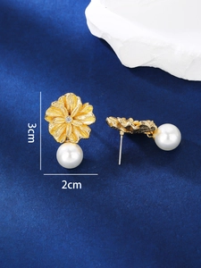 Detailed view of elegant gold floral earrings with zircon and white pearl accents