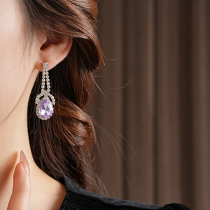 Dettaglio degli orecchini a goccia viola con griglia di diamanti sul collo della modella