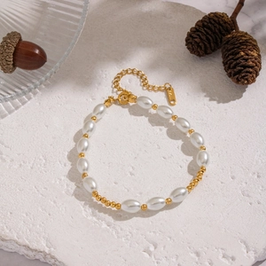 Vue détaillée du bracelet de perles et billes dorées sur une surface en pierre texturée