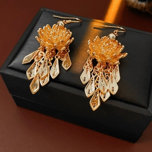Macro view showing detailed gold lotus flower design and tassel pendants on earrings