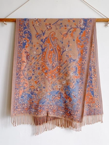 Detail of bohemian paisley shawl with orange and blue patterns and fringe tassels