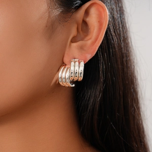 Close-up of a silver multi-layered hoop earring on model showing glossy metallic finish