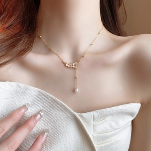 Close-up of Y-shaped necklace featuring enamel flowers and a single white pearl drop