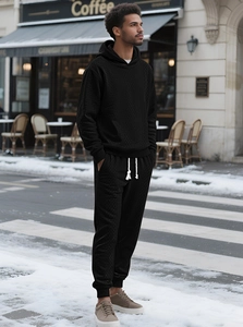 Detail of men's black tracksuit showing geometric jacquard texture and drawstring hoodie
