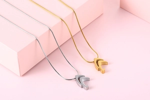Detail of gold and silver snake chain necklaces with hollow chevron arrow pendants
