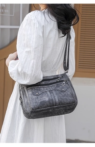 Outdoor shot showing back view of woman wearing dark grey vintage shoulder bag with rivets