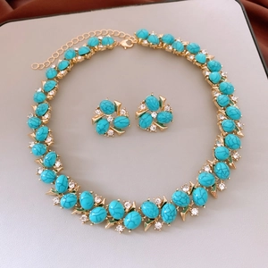 Detailed view of vintage gold necklace and earring set with turquoise stones and zircons