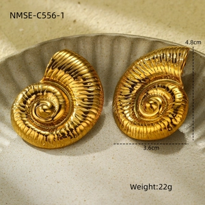 Macro detail of gold snail shell earrings showing spiral texture and polished finish