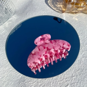 Detailed view of large pink marble acetate hair claw clip with glossy jelly texture finish