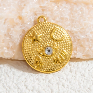 Macro shot of gold stainless steel charm featuring moon, star, and evil eye symbols